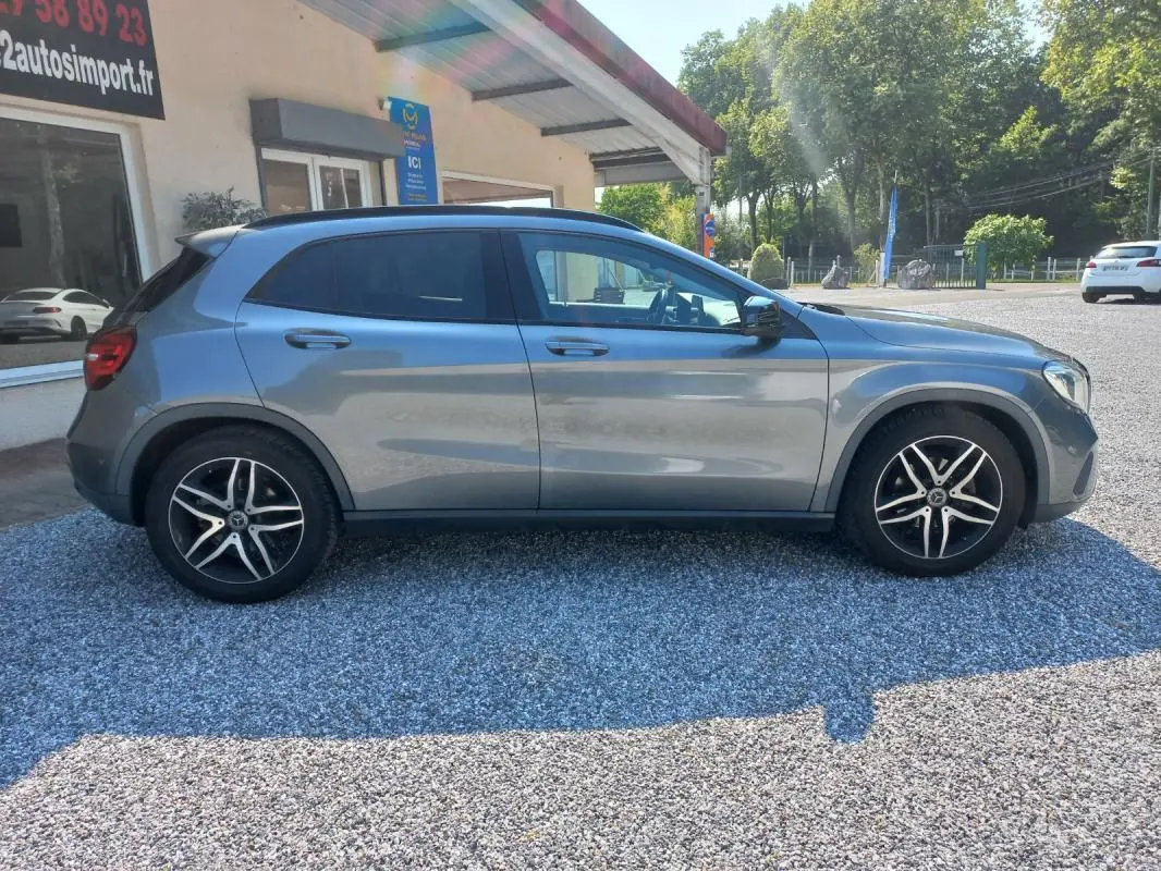 Vue de profil côté gauche d'un Mercedes GLA gris 2019 avec jantes alliage et vitres teintées, stationné sur gravier.