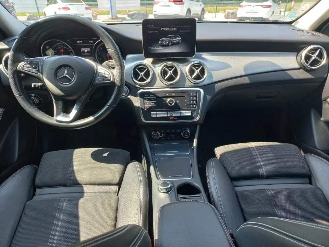 Vue intérieure avant du Mercedes GLA 2019 gris, montrant le tableau de bord, volant multifonction et écran central.