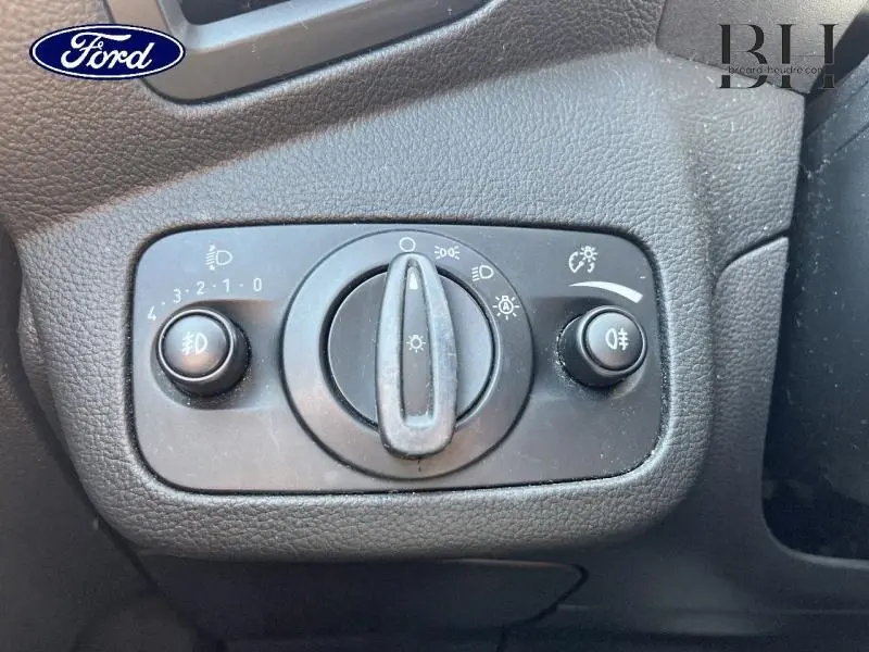 Gros plan sur le panneau de commande des phares du Ford Grand C-MAX blanc glacier, intérieur noir texturé.