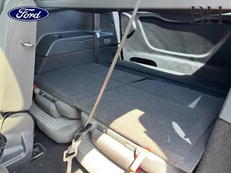 Vue intérieure arrière du Ford Grand C-MAX blanc avec sièges rabattus formant une surface plane de chargement.