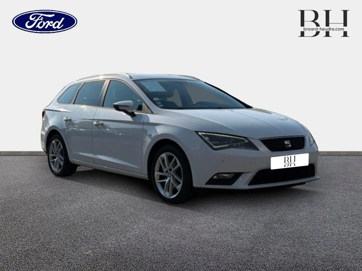 SEAT Leon ST blanc Candy vue 3/4 avant droit, avec jantes alu et barres de toit visibles.