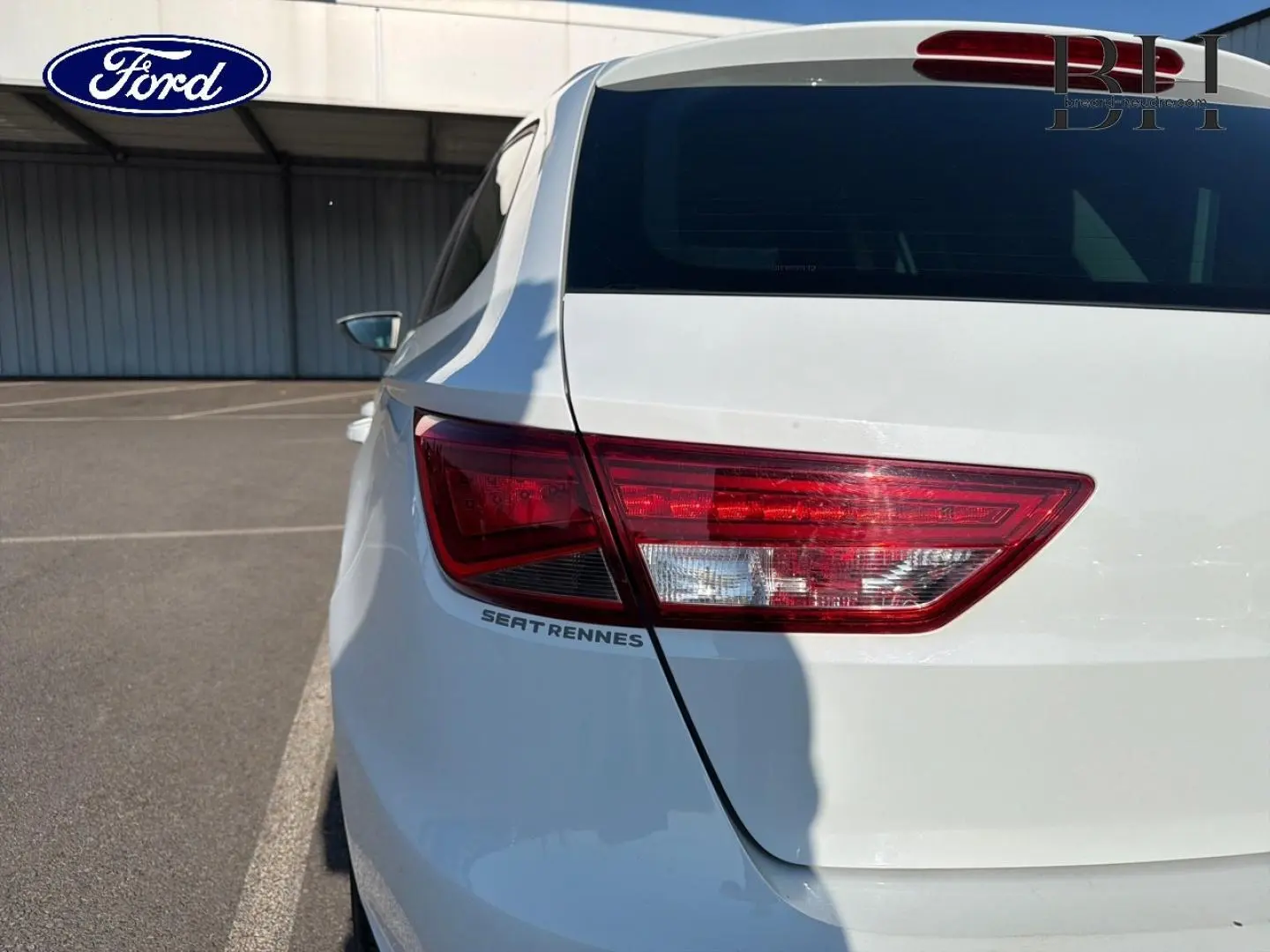 Gros plan sur l'arrière droit blanc candy d'une SEAT LEON ST avec feu arrière et logo SEAT Rennes visible.