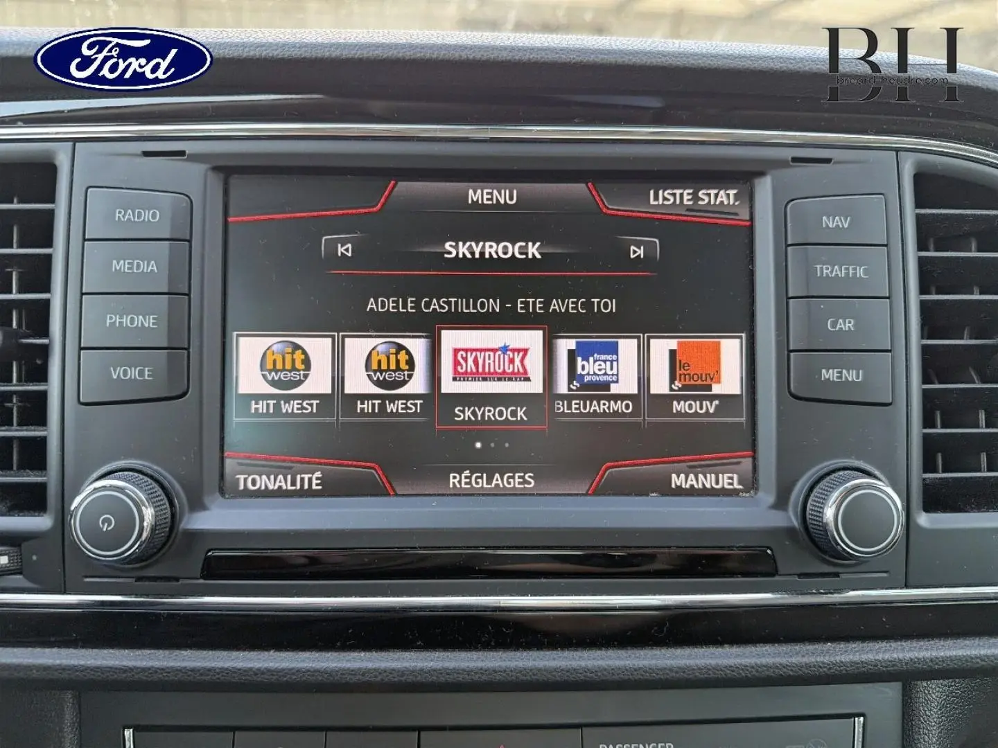 Écran tactile central de la console d'une SEAT LEON ST blanc Candy, affichant les stations radio avec commandes autour.