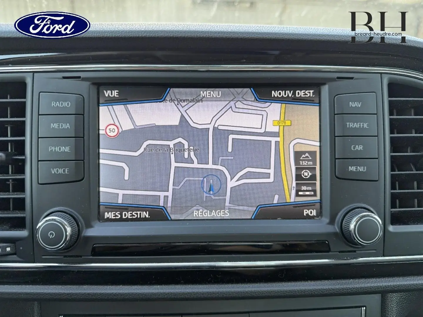 Vue de face sur l'écran tactile du système de navigation d'une SEAT LEON ST blanc Candy, affichant une carte GPS.