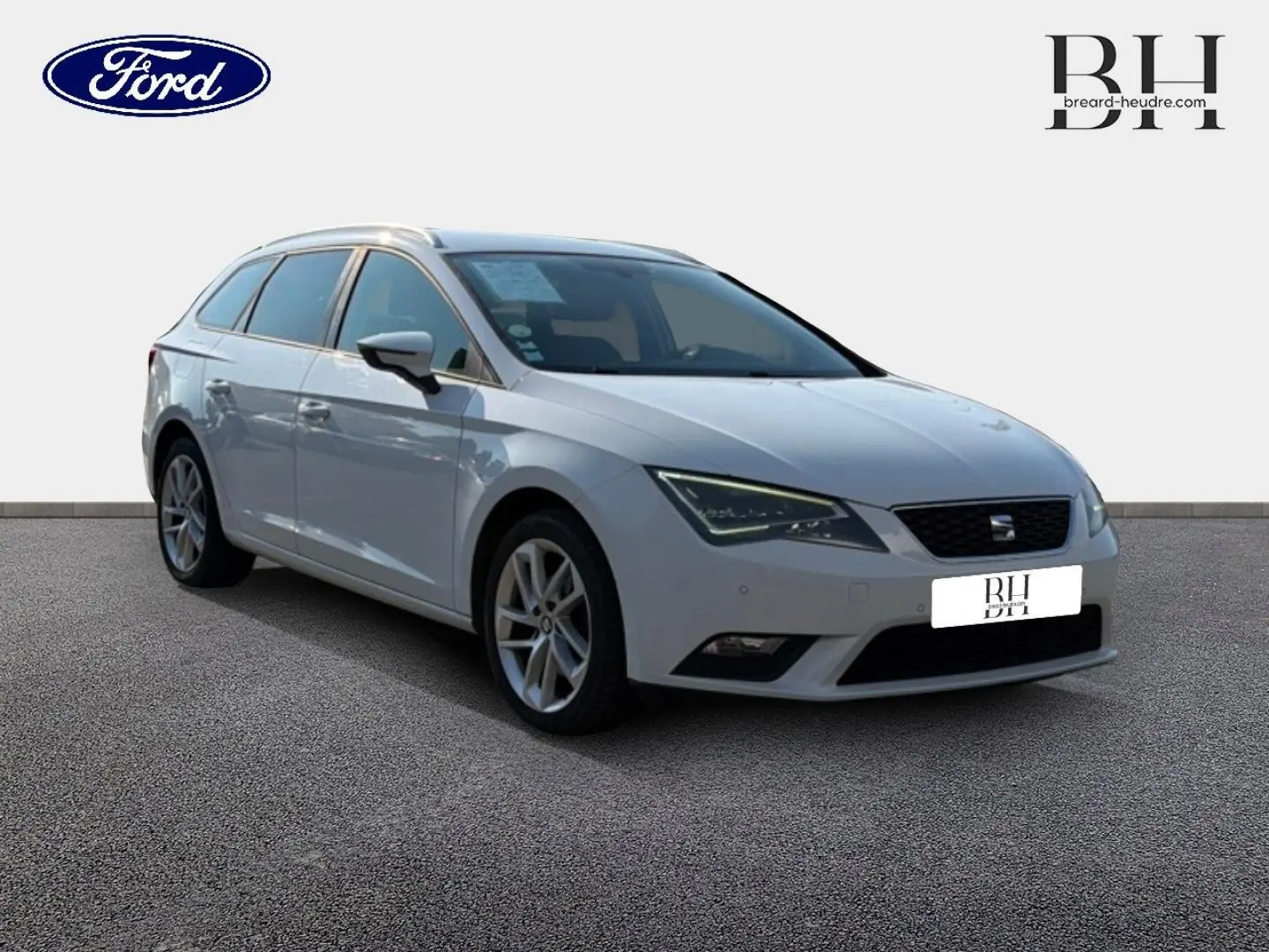 Vue 3/4 avant gauche d'une SEAT LEON ST blanche Candy avec jantes alu et barres de toit visibles.