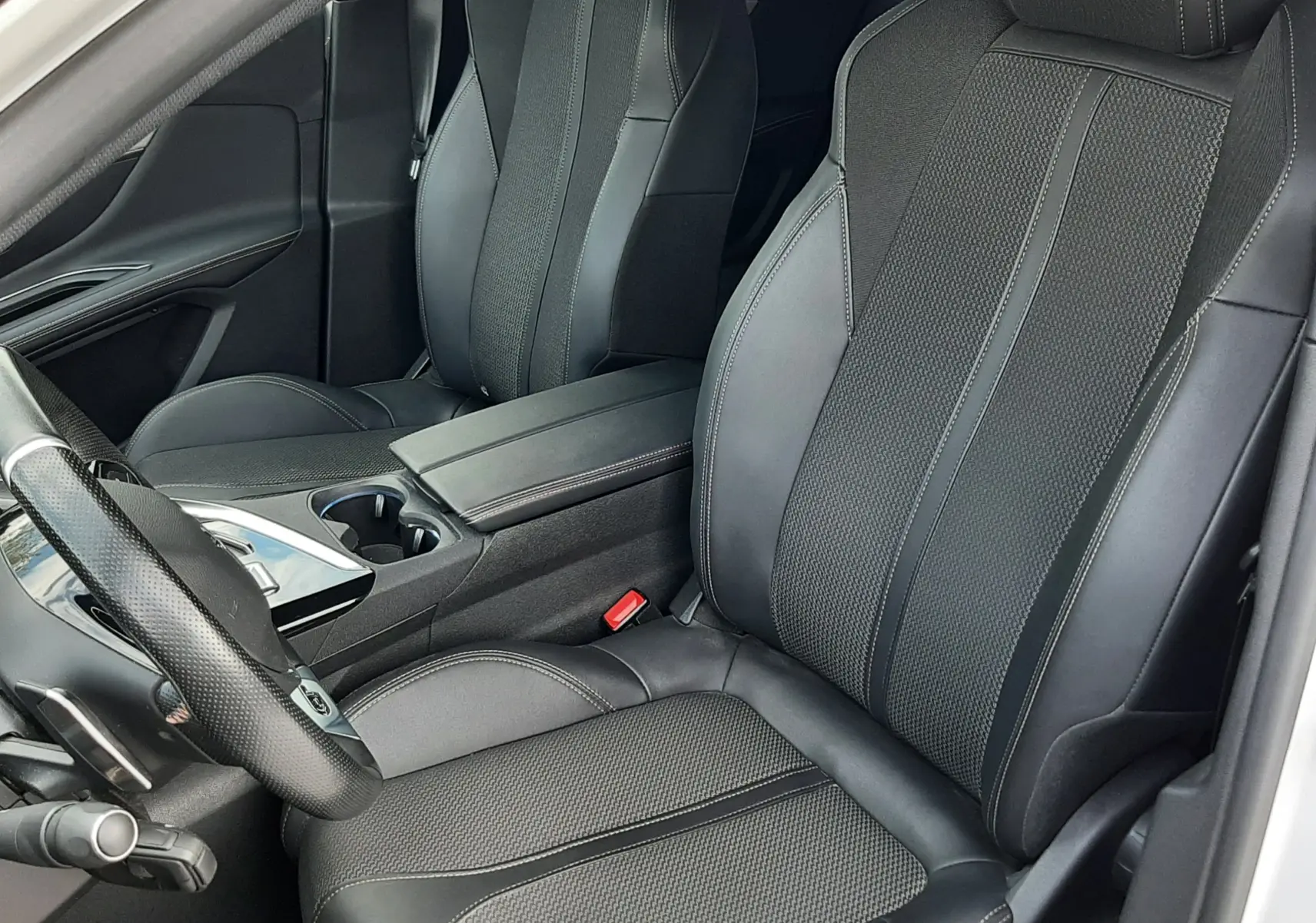 Vue intérieure rapprochée des sièges avant en cuir noir du Peugeot 3008 2022, avec console centrale et volant partiel visible.