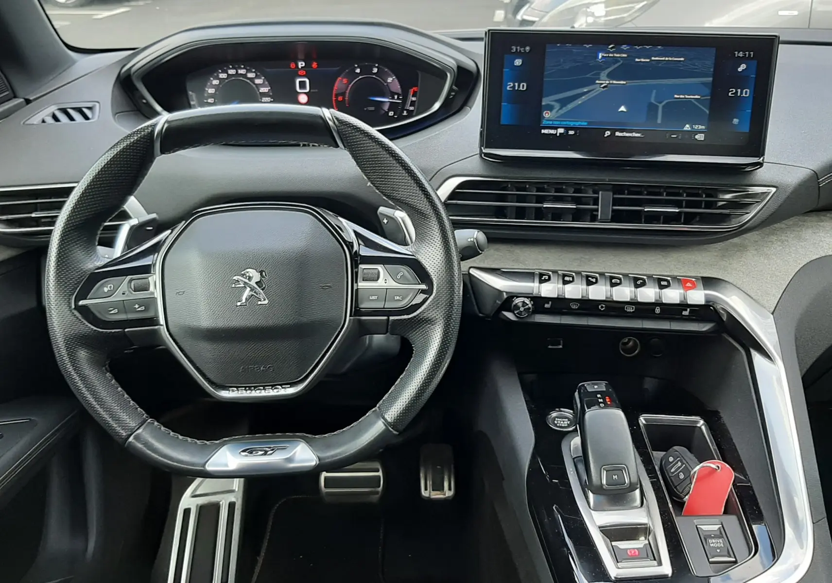 Vue intérieure frontale du poste de conduite du Peugeot 3008 blanc nacré, avec volant compact, écran tactile et console moderne.