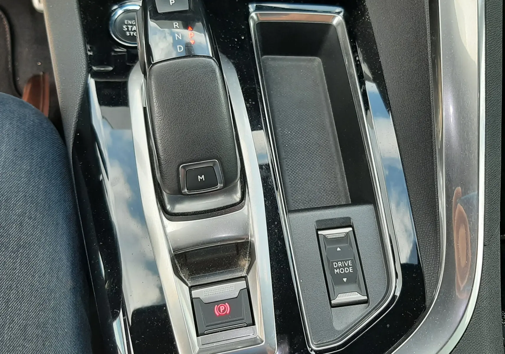 Vue rapprochée de la console centrale noire brillante du Peugeot 3008 1.5 BlueHDi, avec levier de vitesse automatique et bouton Drive Mode.