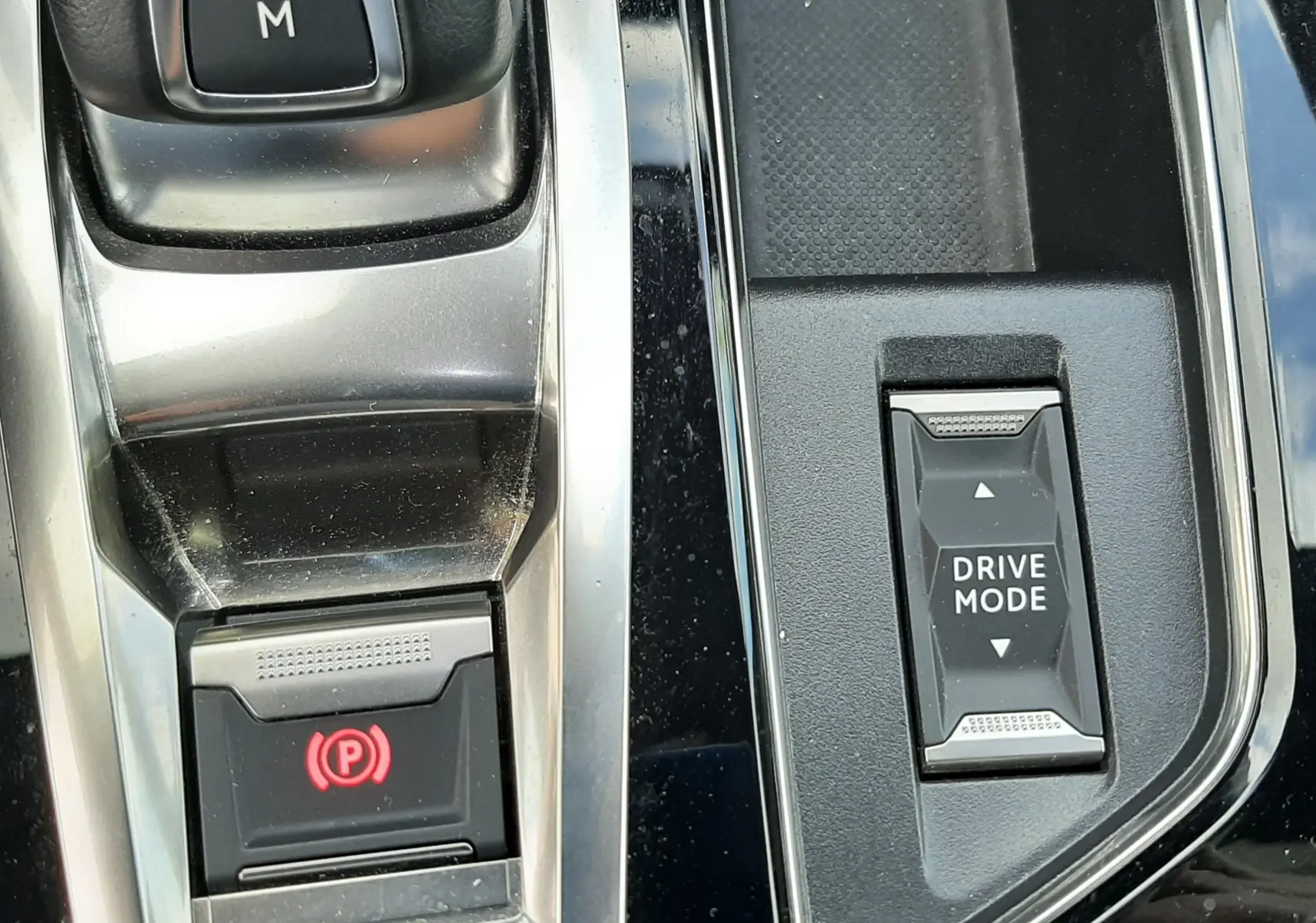 Gros plan sur la console centrale noire du Peugeot 3008 2022, avec bouton Drive Mode et frein à main électronique.