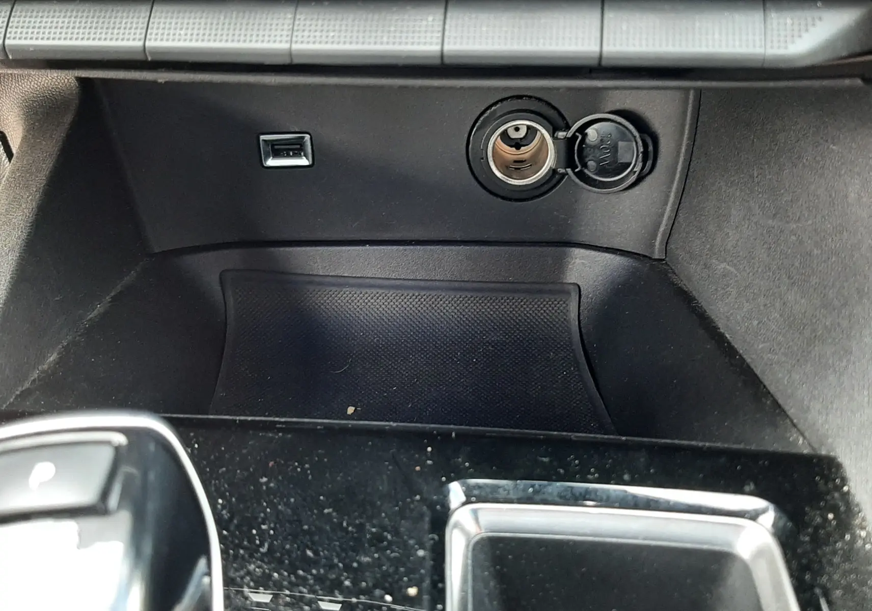 Vue rapprochée de la console centrale noire du Peugeot 3008 2022, montrant prise USB et allume-cigare ouverts.