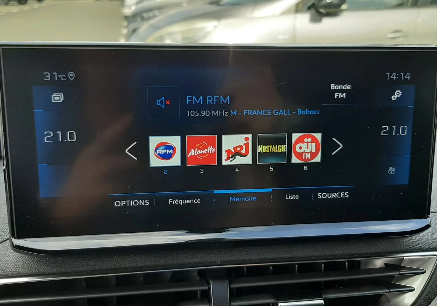 Écran tactile central du Peugeot 3008 2022 affichant les stations radio FM, avec tableau de bord noir et aérateurs dessous.