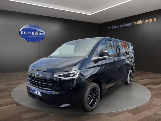 Vue 3/4 avant droit d’un Volkswagen Transporter noir 2026 avec jantes noires et phares LED, en showroom.