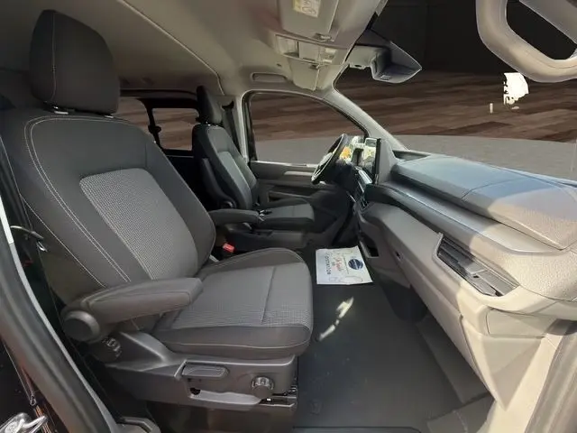 Vue intérieure côté droit du Volkswagen Transporter noir 2026, montrant les sièges avant et le tableau de bord moderne.
