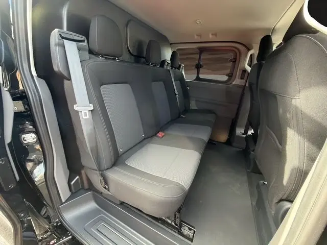 Vue intérieure côté droit du Volkswagen Transporter noir 2026, montrant la banquette arrière 3 places et la cloison pleine.