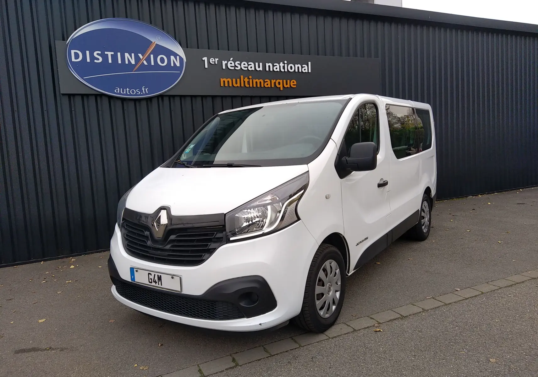 Renault Trafic Microbus blanc vu en 3/4 avant droit, avec calandre noire et vitres teintées arrière.