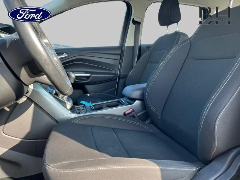Intérieur avant du Ford Kuga 2018, vue côté conducteur, sièges sport noirs avec surpiqûres blanches et accoudoir central.