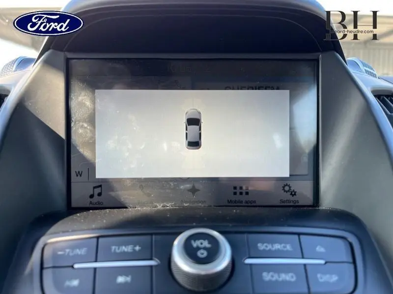 Vue rapprochée de l'écran tactile central du Ford Kuga 2018 affichant l'aide au stationnement, entouré des commandes audio.