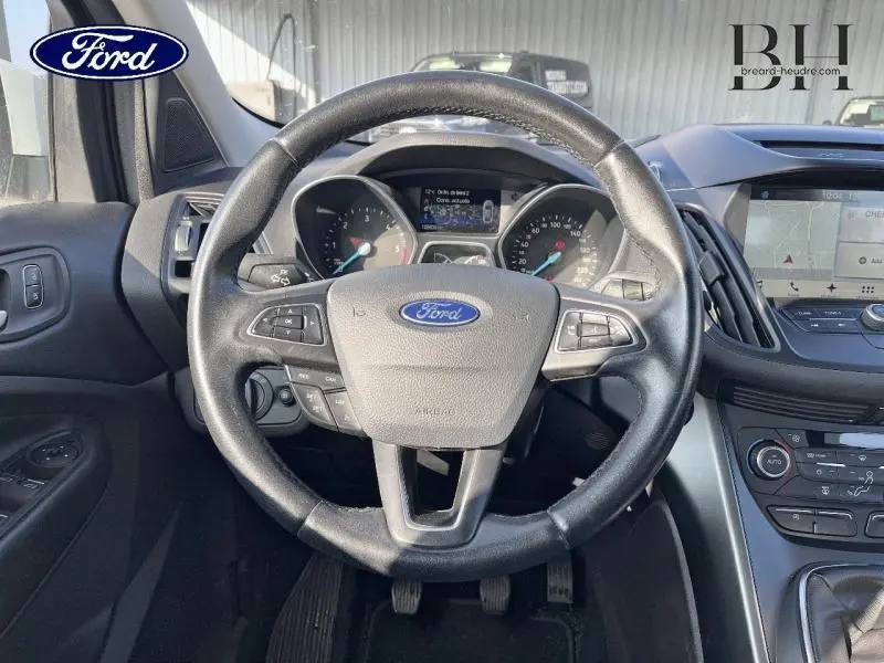 Vue intérieure centrée sur le volant cuir multifonction du Ford Kuga 2018 avec tableau de bord et écran GPS visible.
