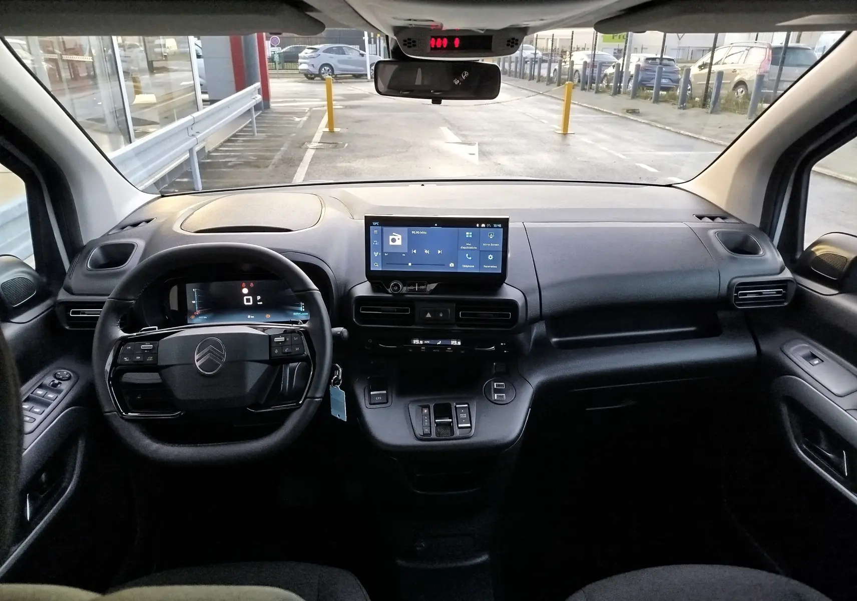 Vue intérieure frontale du tableau de bord noir du Citroën Berlingo 2025 avec écran tactile central et volant multifonction.