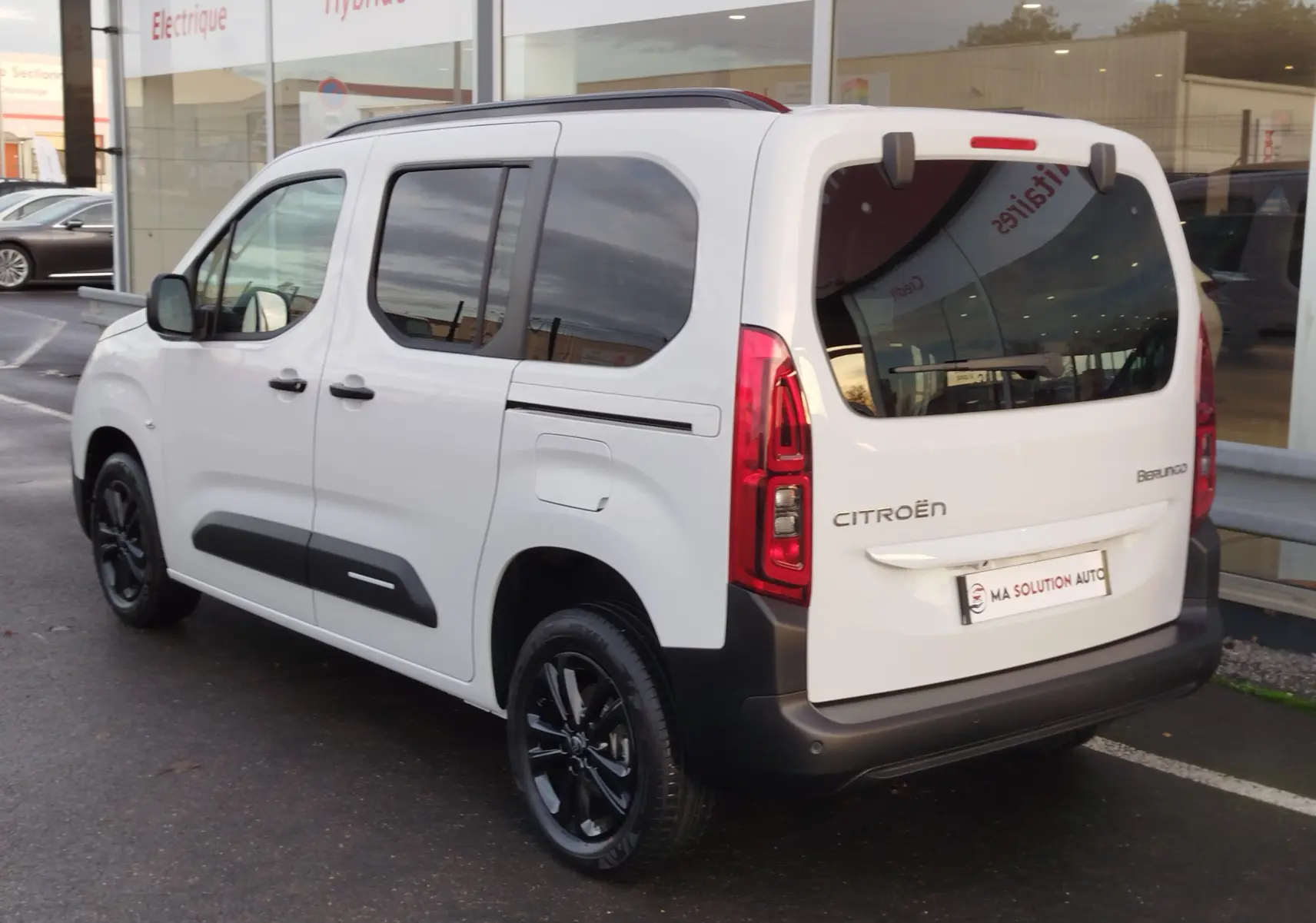 Vue 3/4 arrière droite du Citroën Berlingo blanc Kaolin avec vitres teintées et jantes noires brillantes.