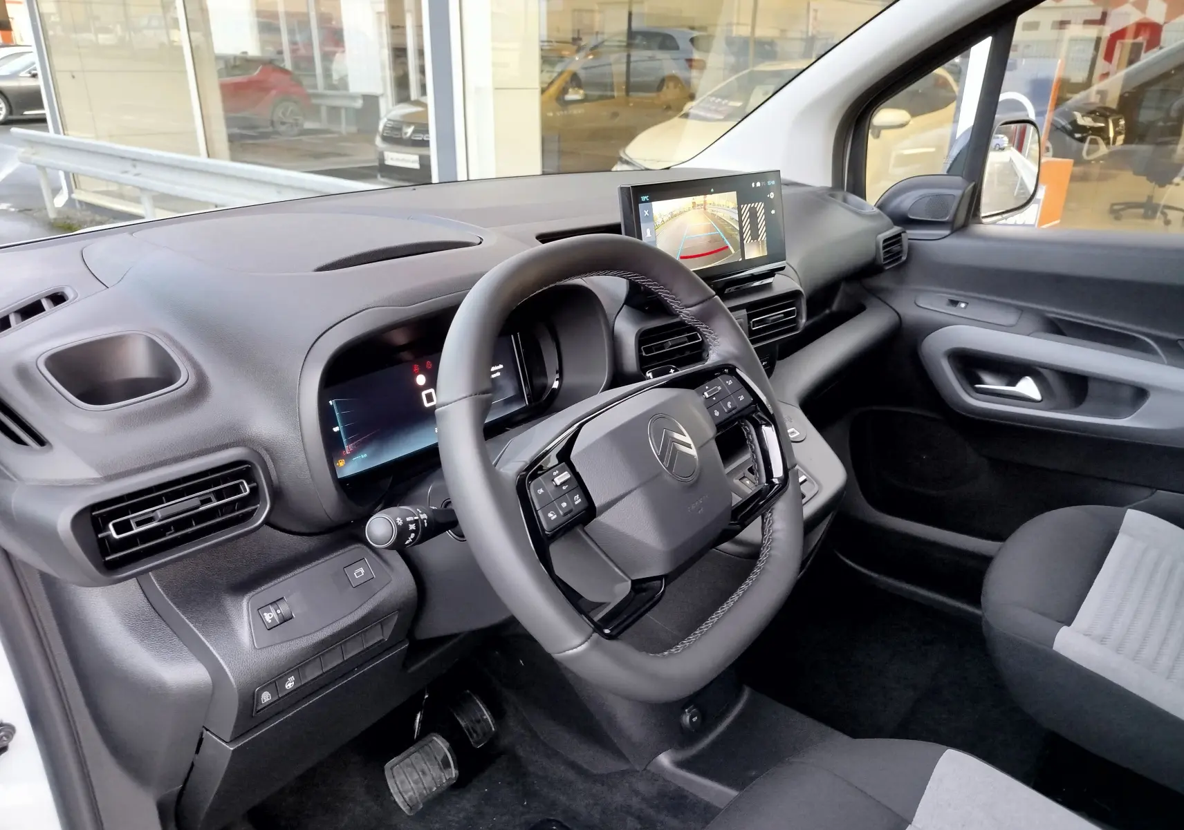 Vue intérieure côté conducteur du Citroën Berlingo 2025 blanc, avec tableau de bord numérique et écran tactile de recul.