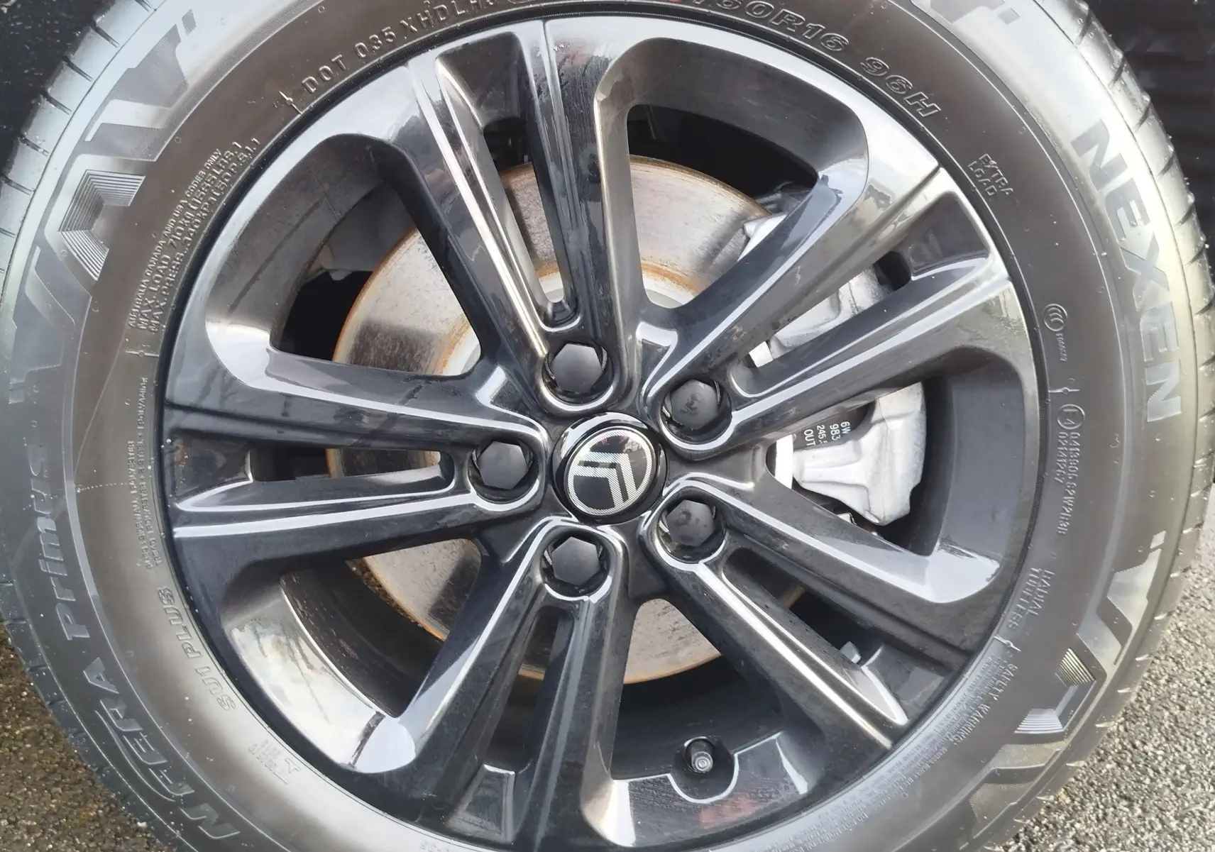 Gros plan sur la jante noire brillante d’une Citroën Berlingo 2025 avec logo central et pneu Nexen visible.