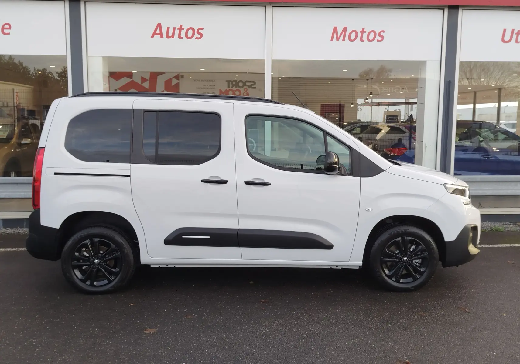 Vue de profil côté droit d'un Citroën Berlingo blanc Kaolin avec jantes noires et protections latérales noires.