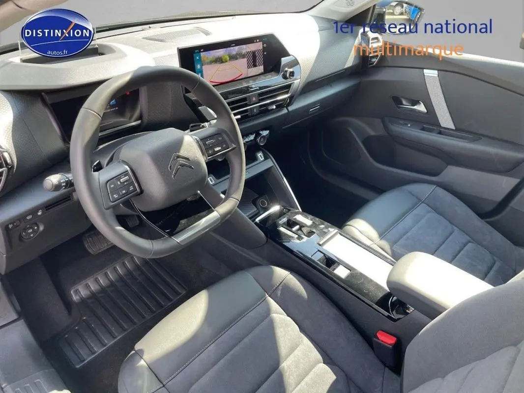 Vue intérieure côté conducteur de la Citroën C4 2024, tableau de bord moderne avec écran tactile et volant cuir noir.