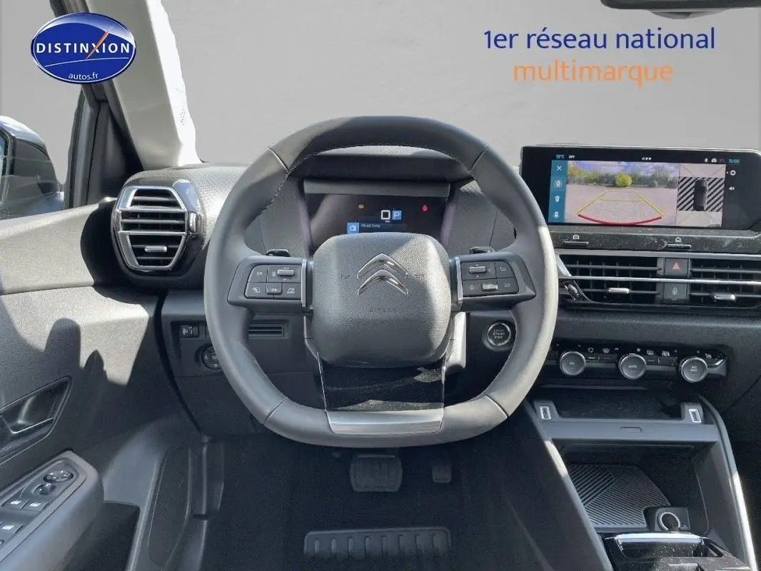 Vue intérieure centrée sur le volant cuir de la Citroën C4 2024 avec écran tactile et caméra de recul affichée.