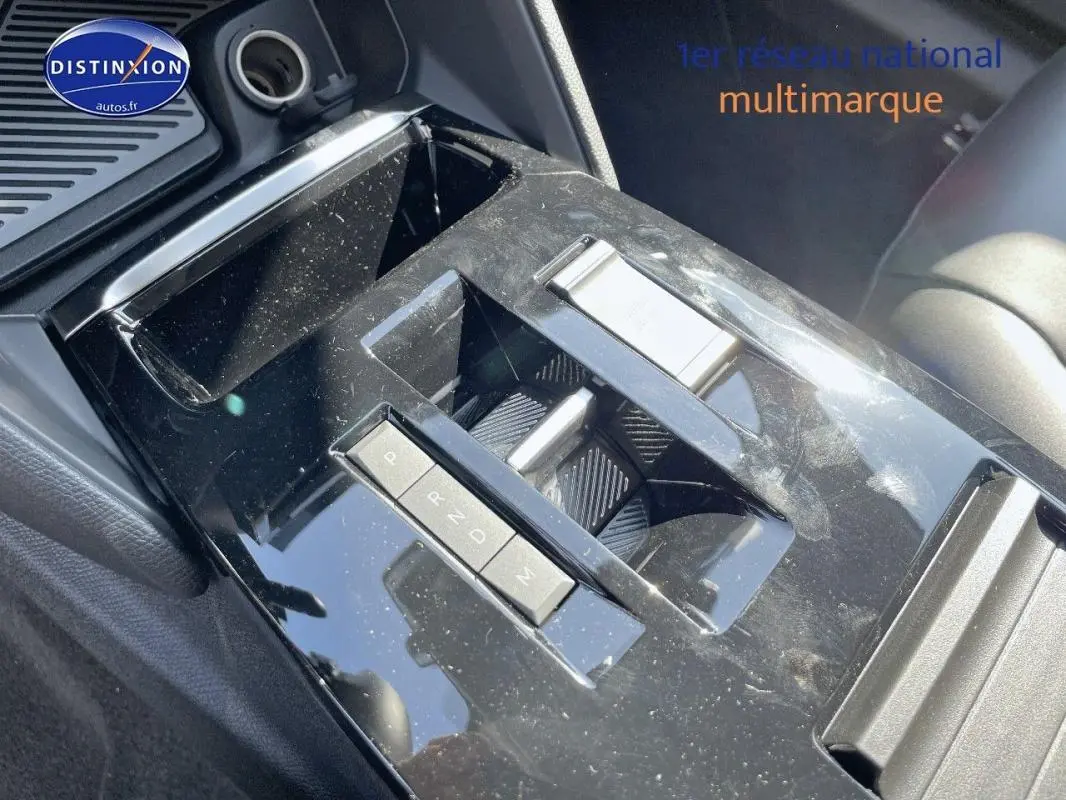 Gros plan sur la console centrale noire brillante de la Citroën C4 2024 avec commandes de boîte automatique et rangement.