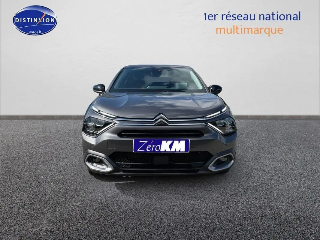 Vue frontale d'une Citroën C4 platine 2024 avec feux LED et calandre distinctive, sur sol gris neutre.