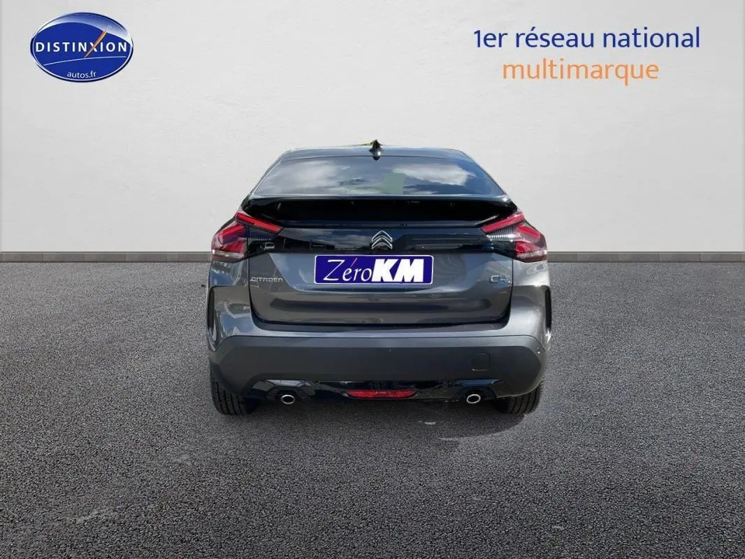 Vue arrière d'une Citroën C4 platine 2024 avec feux LED et double sortie d'échappement visible sur sol goudronné.