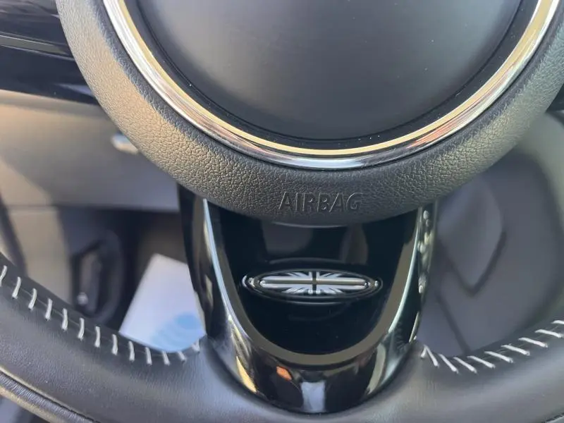 Gros plan sur le volant cuir noir du MINI Countryman avec logo Union Jack et surpiqûres blanches visibles.
