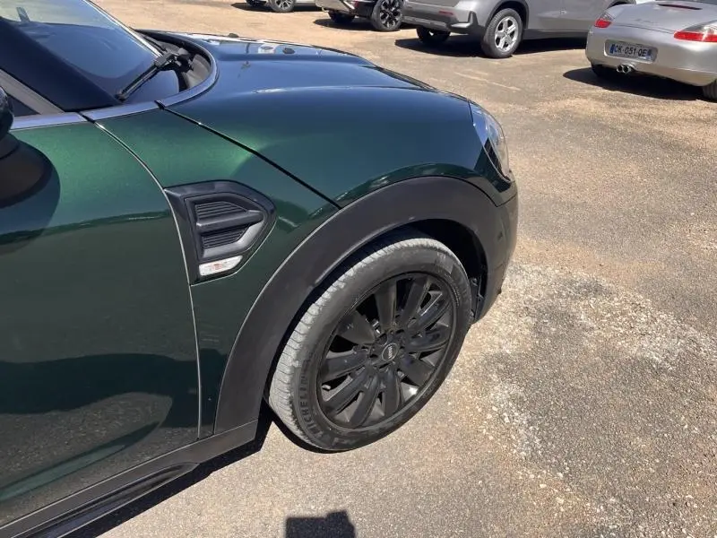 Gros plan sur l'aile avant gauche d'une MINI Countryman British Racing Green avec jante noire et prise d'air latérale.