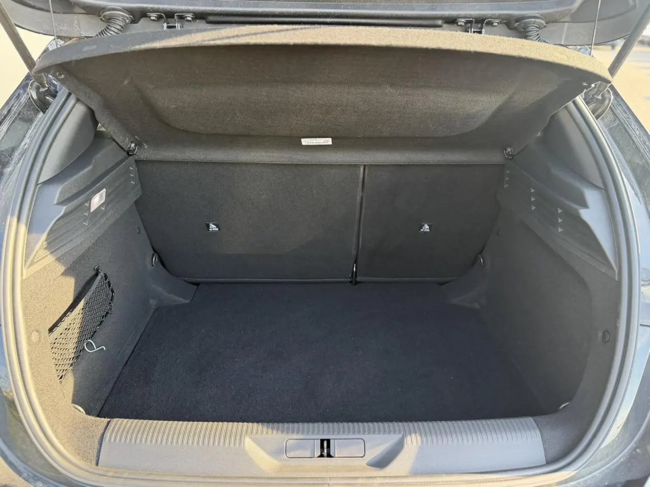 Coffre ouvert de la Peugeot 308 noir Perla, vue arrière montrant l'espace de chargement vide et les finitions intérieures.