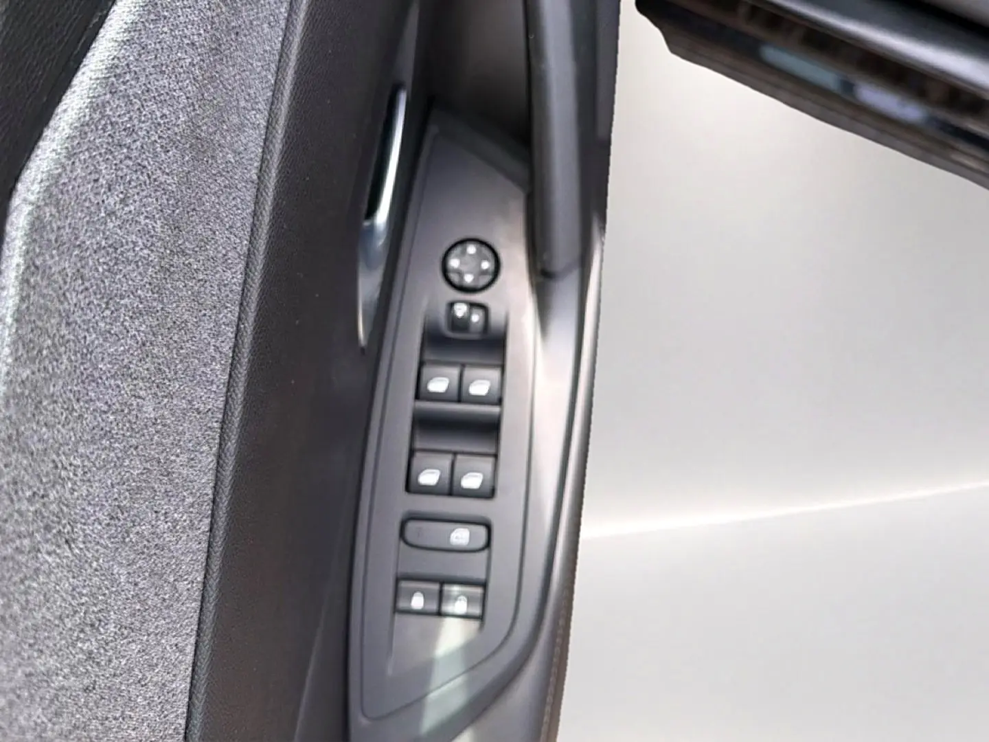 Vue rapprochée du panneau de commandes des vitres côté gauche, avec matériaux noirs et tissu gris sur la porte d'une Peugeot 408 2024.
