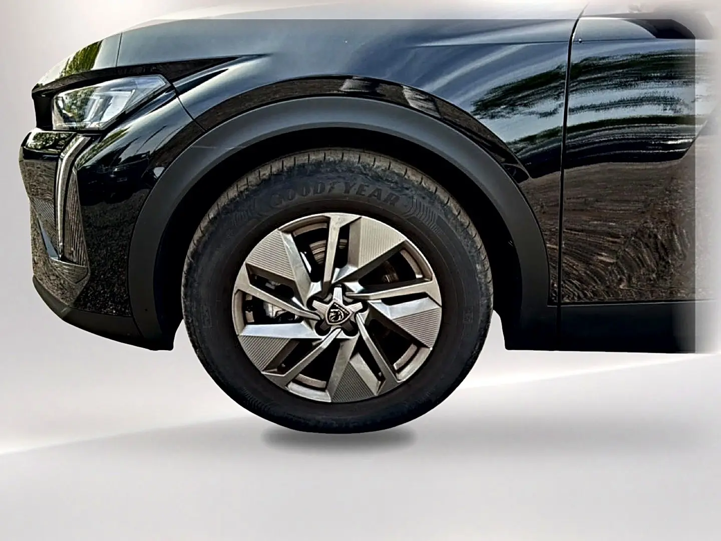 Gros plan sur la roue avant gauche et partie du pare-chocs avant noir brillant du Peugeot 408 Hybrid 136 allure 2024.