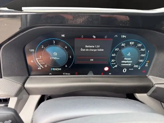 Vue rapprochée du combiné d'instruments numérique du Volkswagen Transporter gris foncé, affichant un message batterie 12V faible.