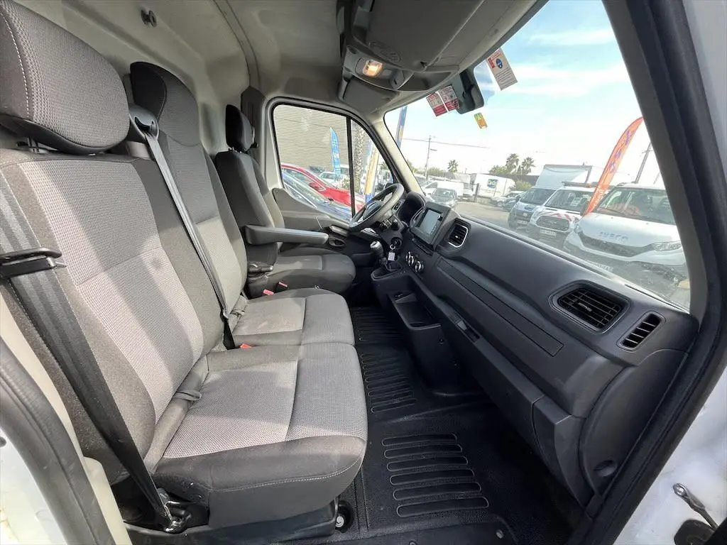Vue intérieure côté passager du Renault Master blanc 2021, montrant les sièges gris et le tableau de bord noir.