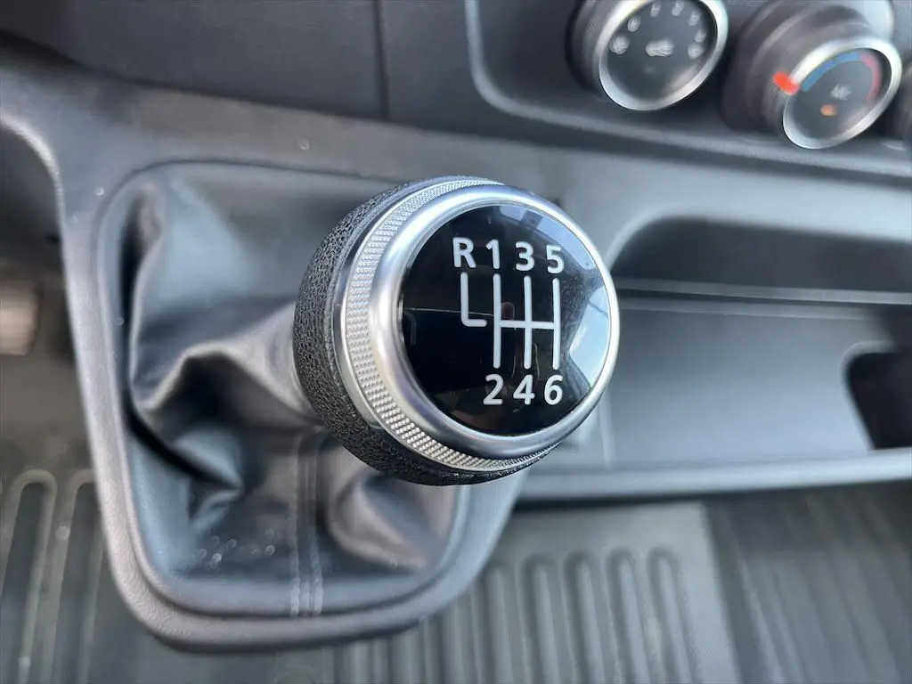 Gros plan sur le levier de vitesses manuel noir et argenté du Renault Master 2021, avec tableau de bord en arrière-plan.