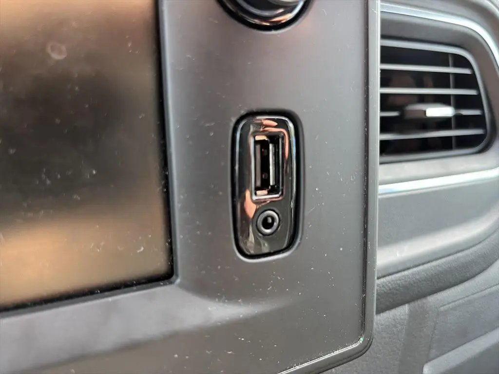 Gros plan sur la prise USB et la prise jack intégrées dans la console centrale noire du Renault Master blanc, côté droit.