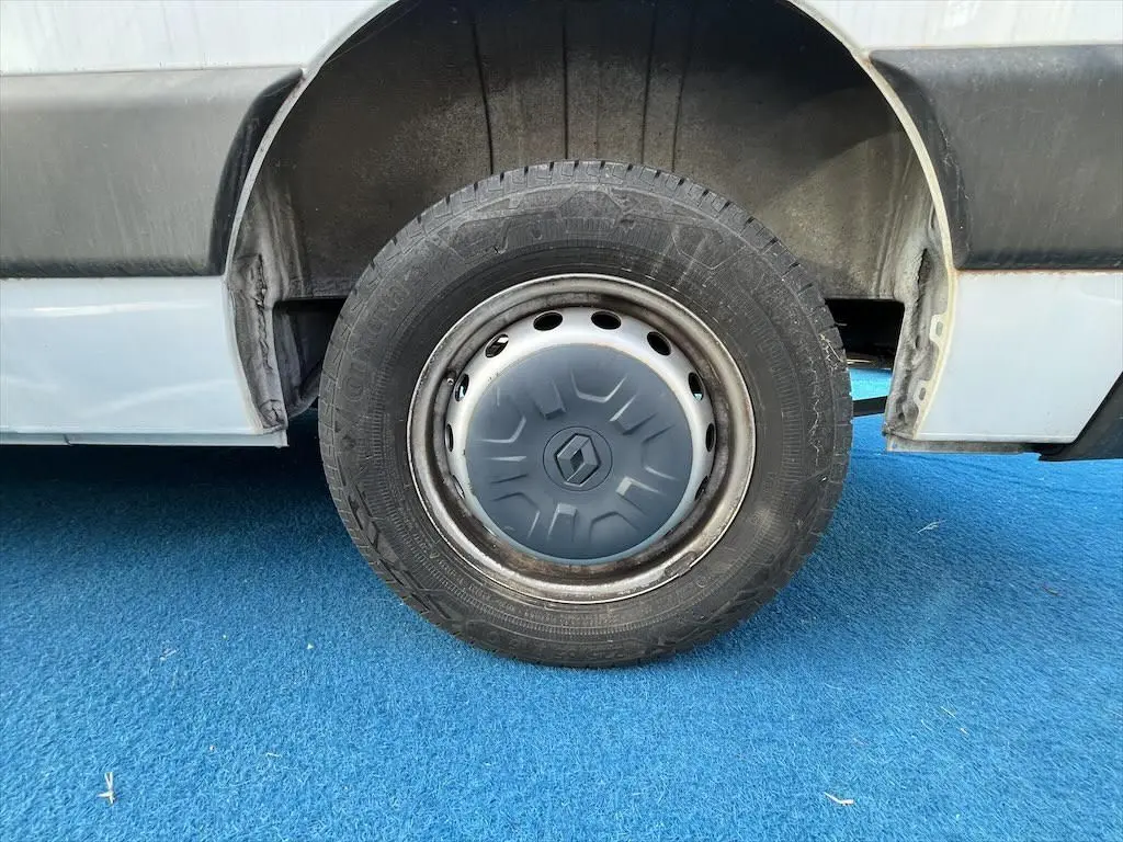 Gros plan sur la roue arrière droite d'un Renault Master blanc avec jante acier et enjoliveur gris.