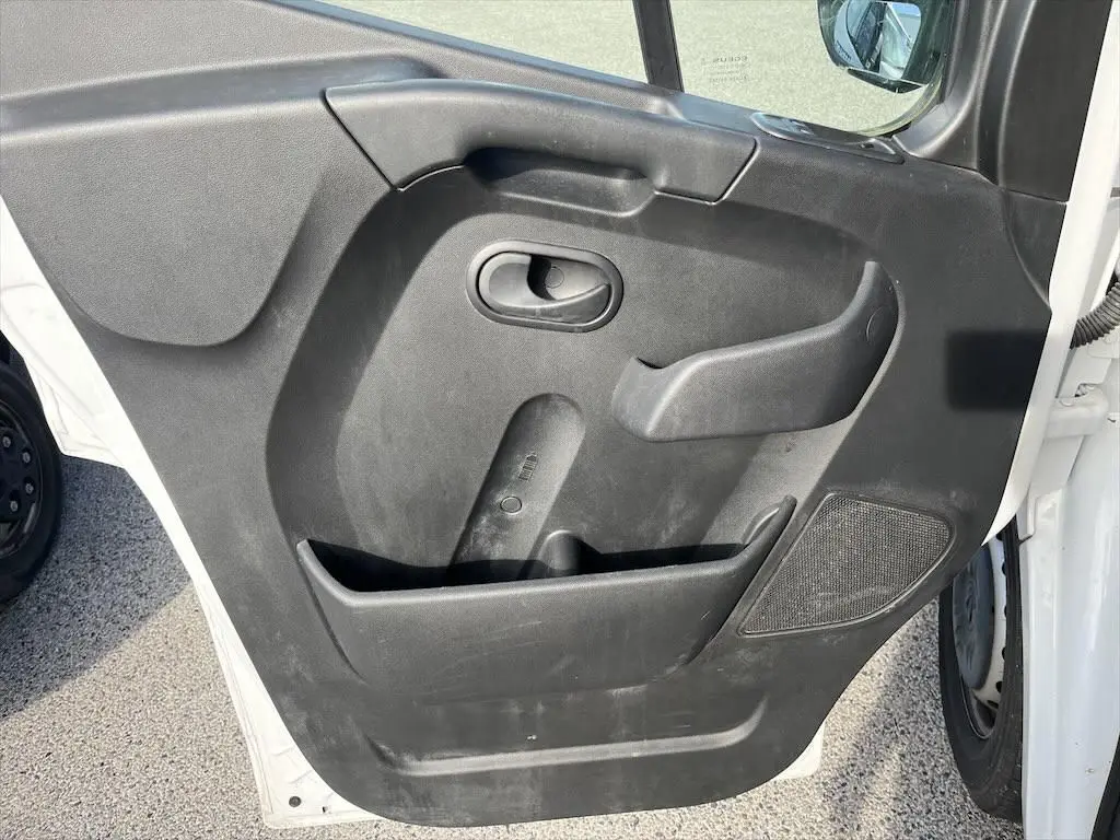 Gros plan sur la porte avant gauche noire du Renault Master blanc, montrant la poignée et le haut-parleur intégré.