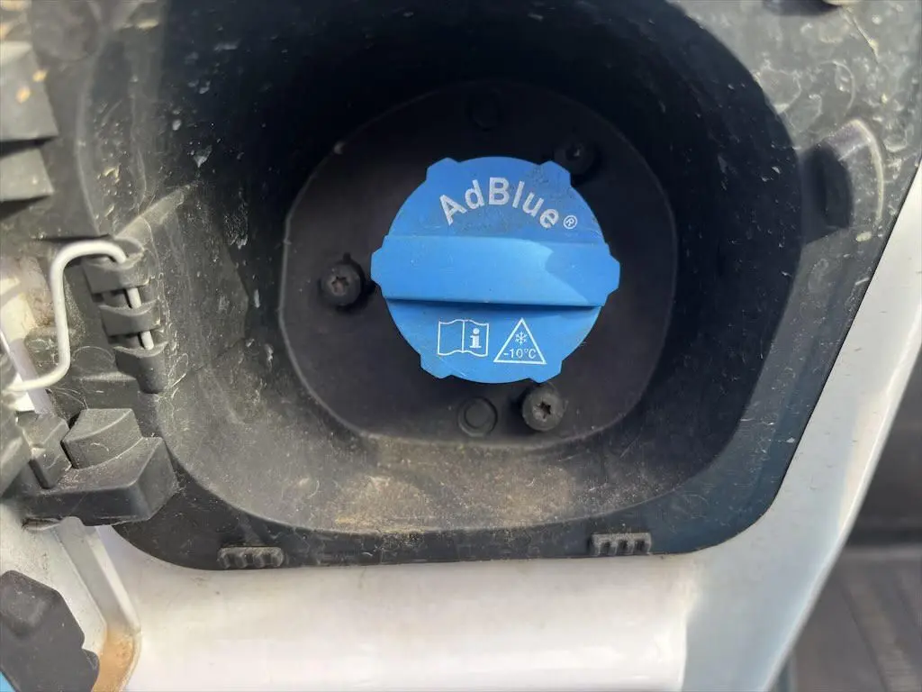 Bouchon bleu AdBlue en gros plan dans l'orifice de remplissage du réservoir d'un Renault Master blanc.