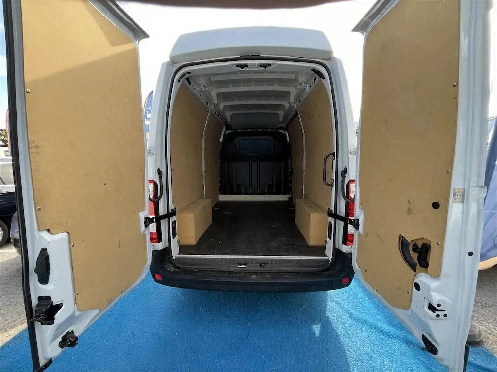 Vue arrière du Renault Master blanc 2021 avec portes ouvertes montrant l'espace de chargement vide et protégé par des panneaux en bois.
