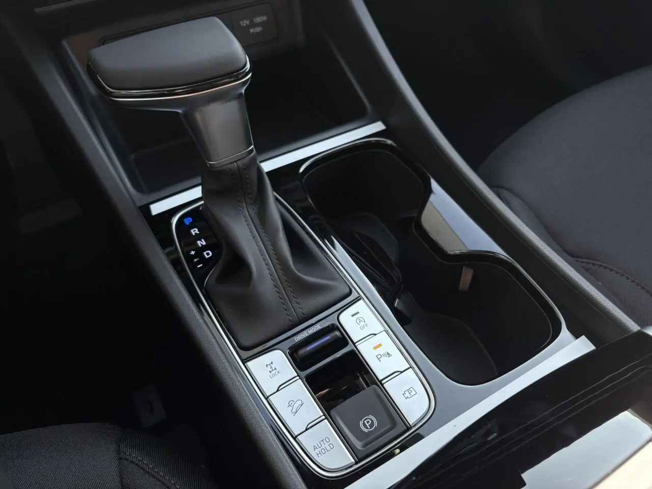 Gros plan sur la console centrale du Hyundai Tucson 2025 avec levier de vitesse automatique et commandes de stationnement.