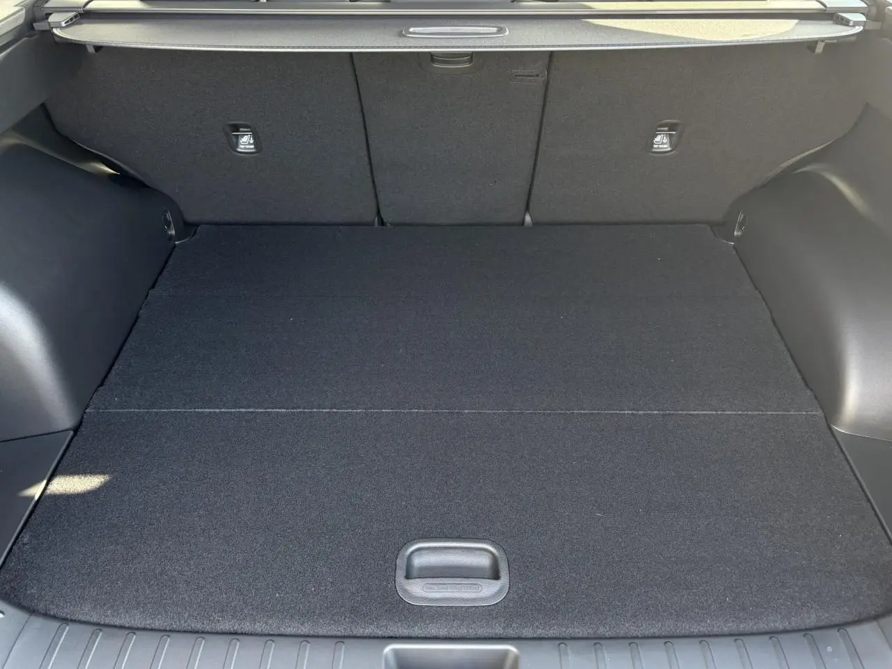 Coffre spacieux du Hyundai Tucson 2025 en Abyss Black, vue intérieure arrière avec plancher plat et revêtement noir.