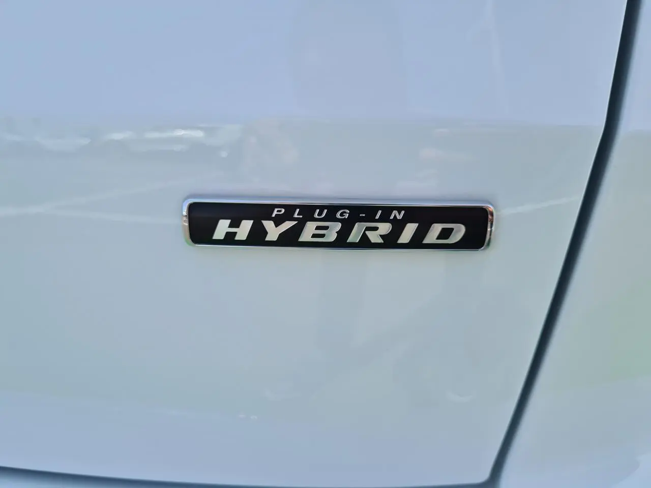 Gros plan sur l’inscription Plug-in Hybrid sur la porte blanche glacier d’un Ford Kuga hybride rechargeable.
