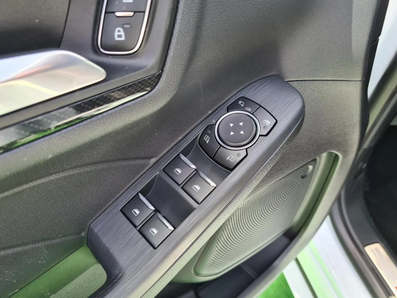 Gros plan sur les commandes de vitres et rétroviseurs côté conducteur du Ford Kuga blanc glacier 2022.