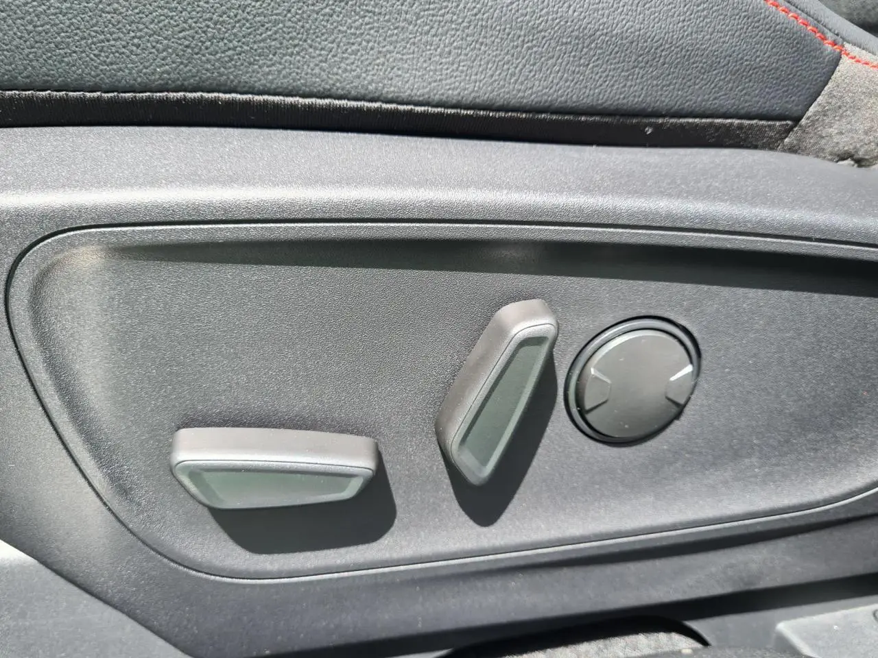 Gros plan sur les commandes électriques de réglage du siège avant côté conducteur du Ford Kuga blanc glacier 2022.